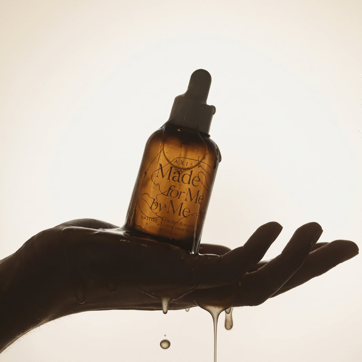 AXIS-Y Biome Radiating Intensified Essence dropper bottle resting in an open palm with essence dripping between the fingers