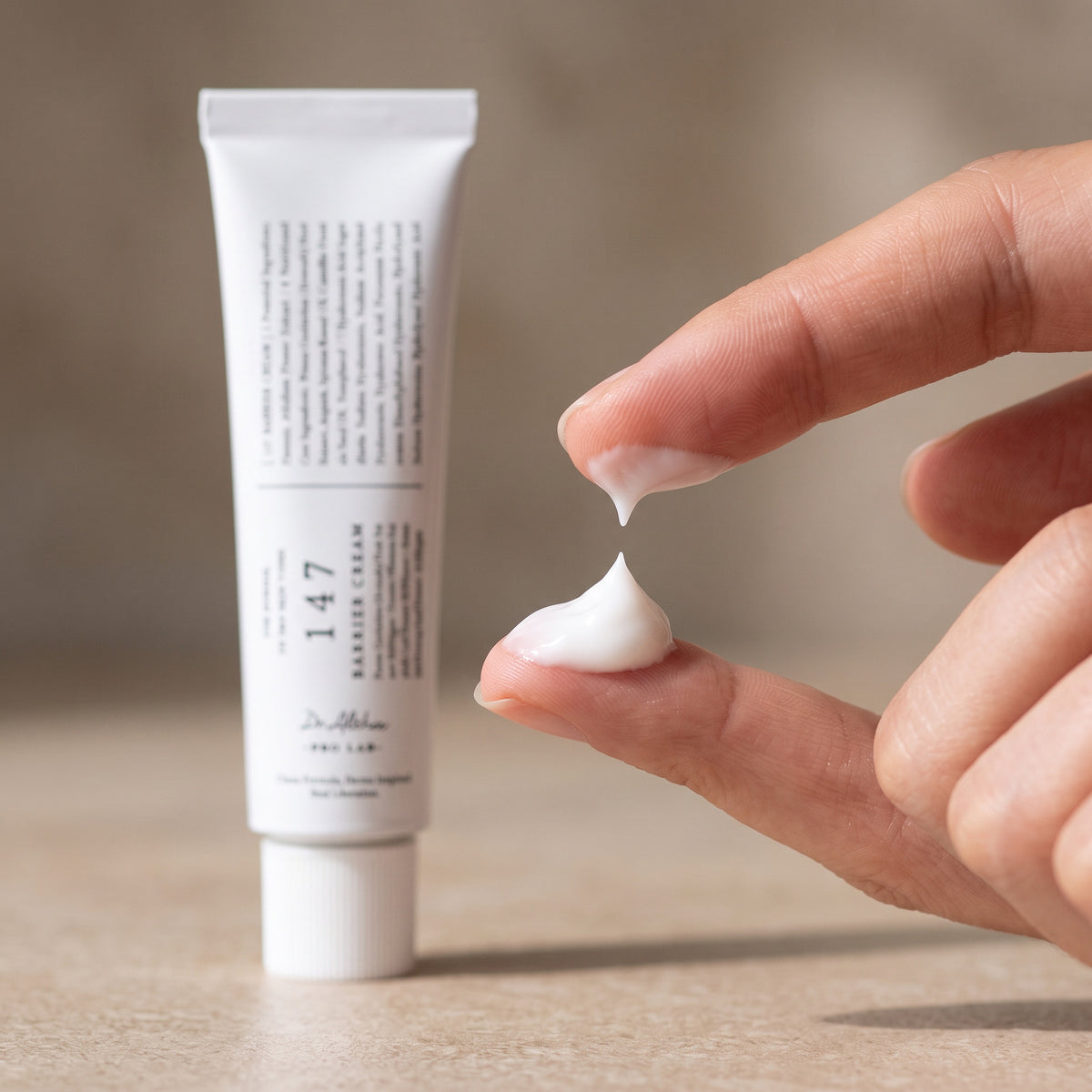 Rich white DR.ALTHEA 147 Barrier Cream on a fingertip beside the 147 Barrier Cream tube