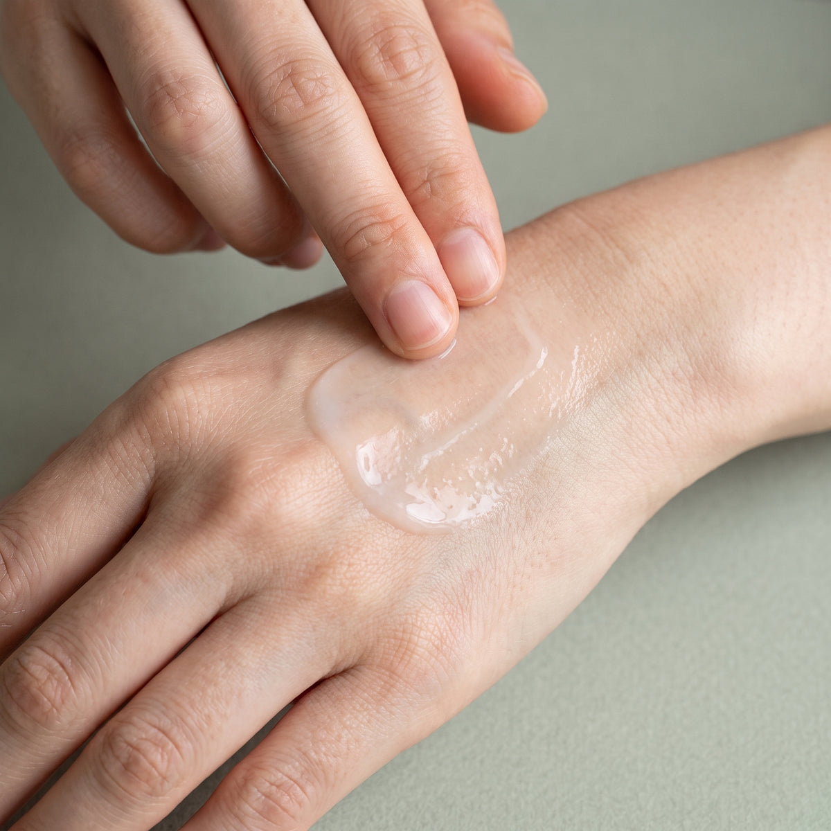A milky, watery relief gel spread across the back of a hand with two fingertips into an almost invisible film