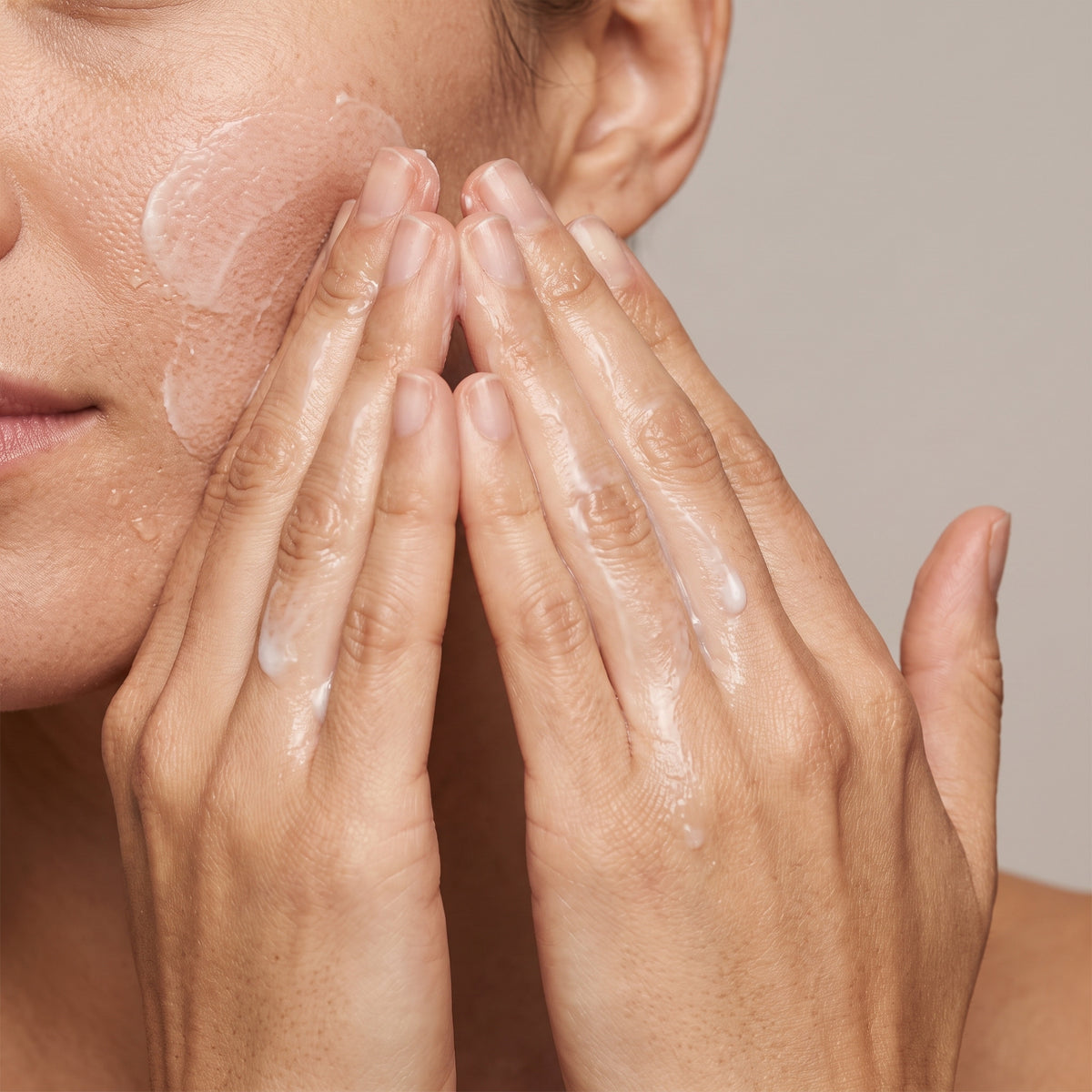 Two hands massaging the pale Dr.Althea Pore Refresh cleansing balm over the cheeks as it turns milky with water