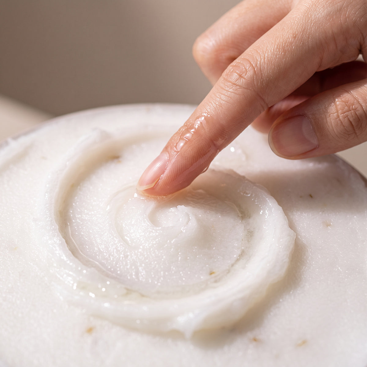 A fingertip drawing a swirl through the white sorbet-textured Dr.Althea Pure Grinding Cleansing Balm as it begins to melt to oil