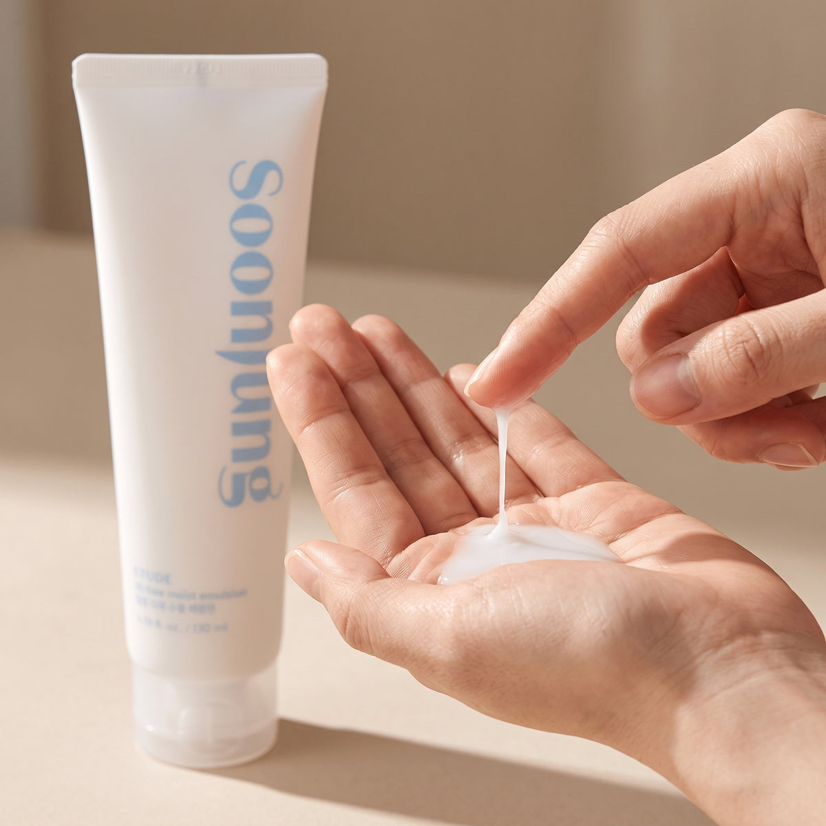Thin milky ETUDE Soon Jung 10-Free Moist Emulsion running into an open palm beside its tube