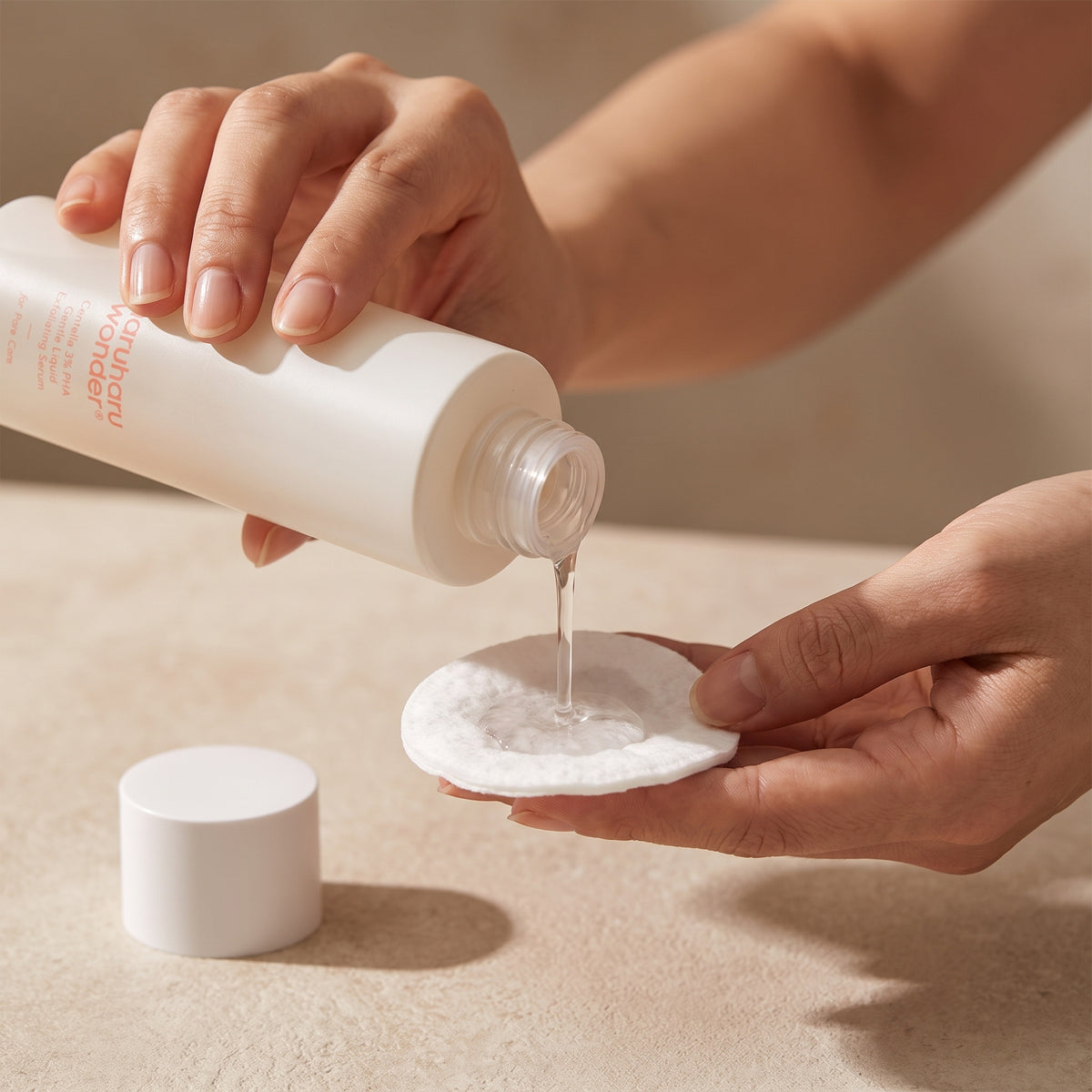 Clear HARUHARU WONDER Centella 3% PHA Gentle Liquid Exfoliating Serum poured from the open bottle onto a cotton pad