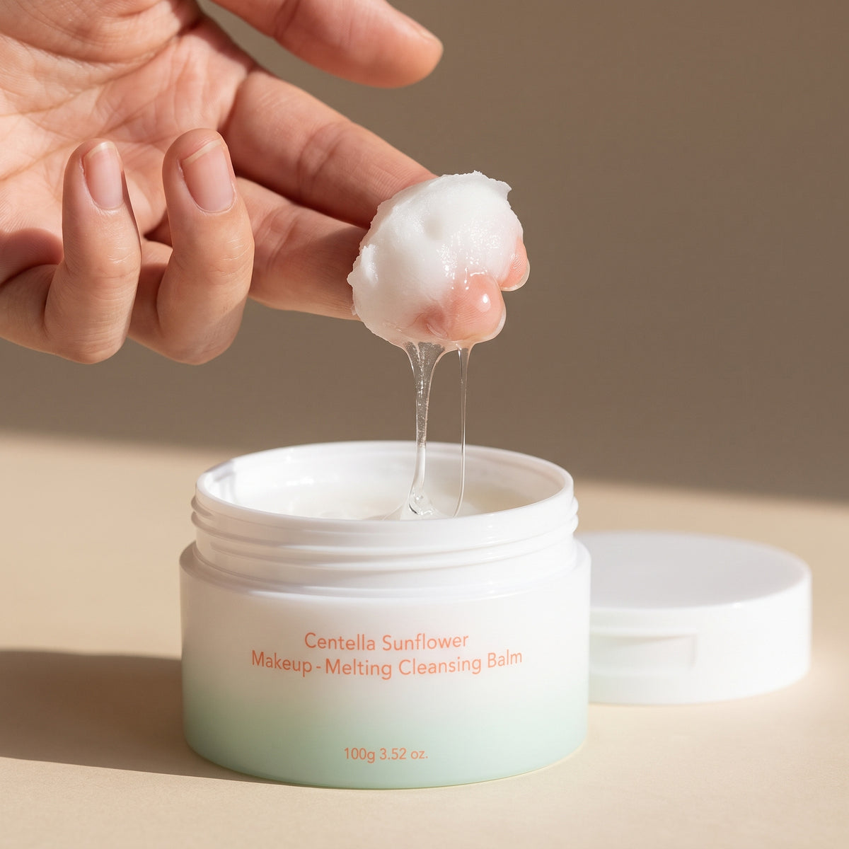 White sherbet HARUHARU WONDER Centella Sunflower Makeup-Melting Cleansing Balm melting to a clear oil on the fingertips above its open jar